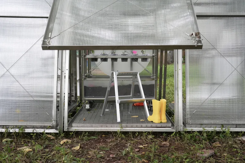 Ground-level view showing yellow boots and cultivation tools stored beneath the raised frame platform