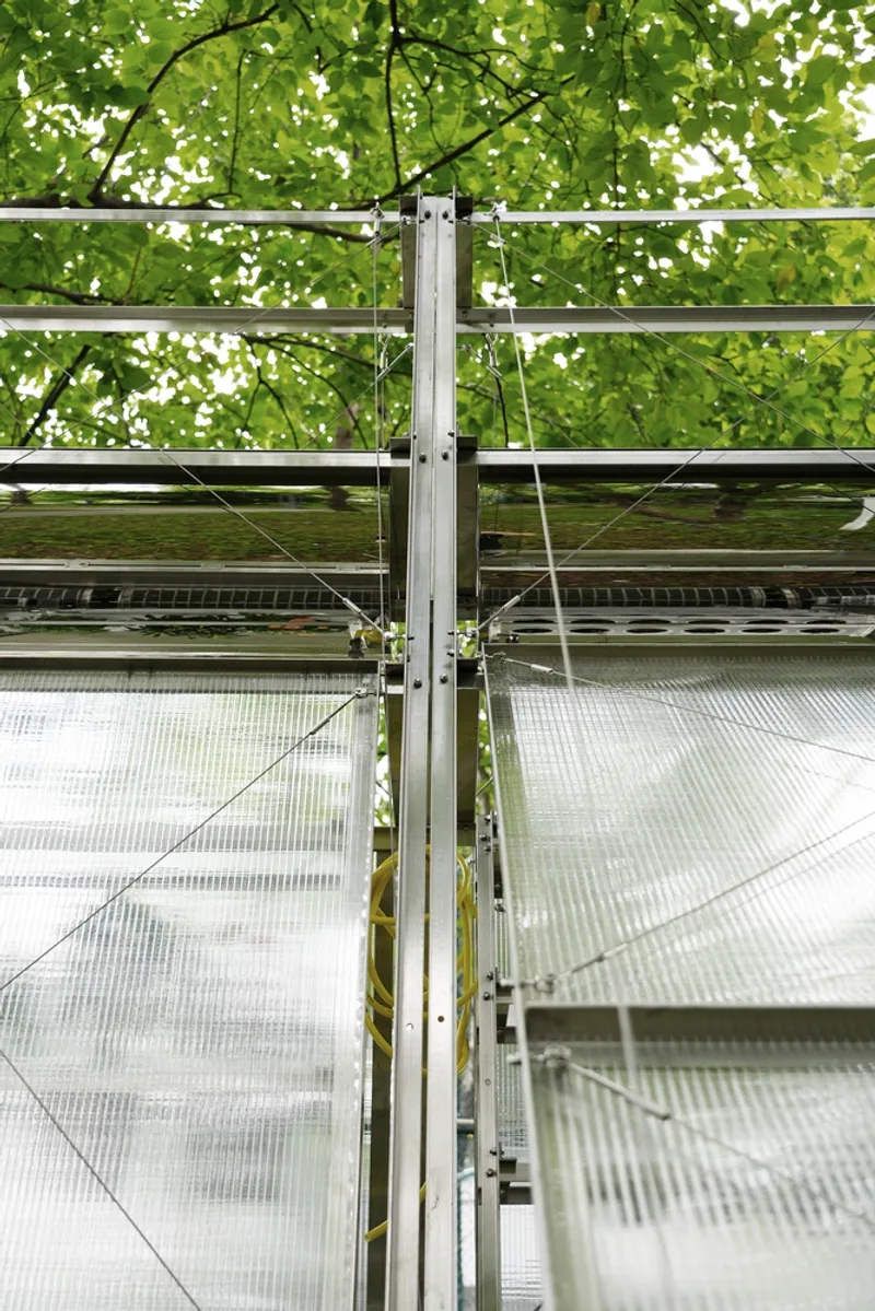 Detail of aluminum column junction with cable bracing and translucent polycarbonate sheets behind