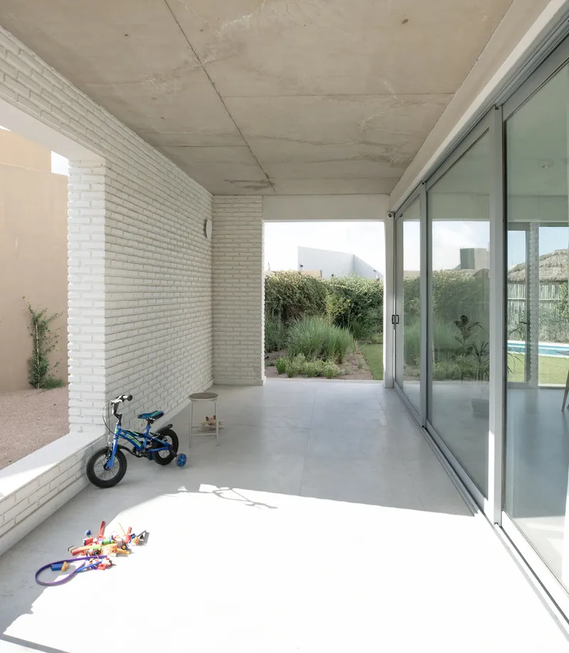 Covered patio with exposed concrete ceiling and white brick wall beside a bicycle
