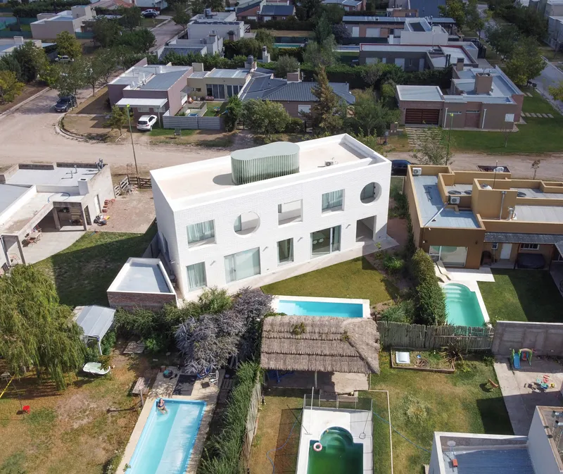 Aerial view showing the white volume with circular window openings and rear swimming pool