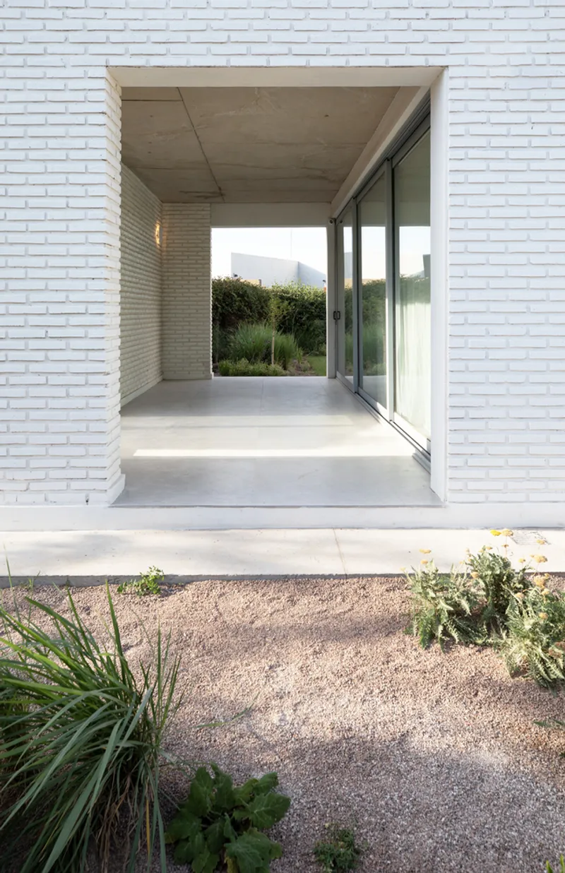 Recessed entry porch with concrete ceiling and sliding glass door framing distant vegetation