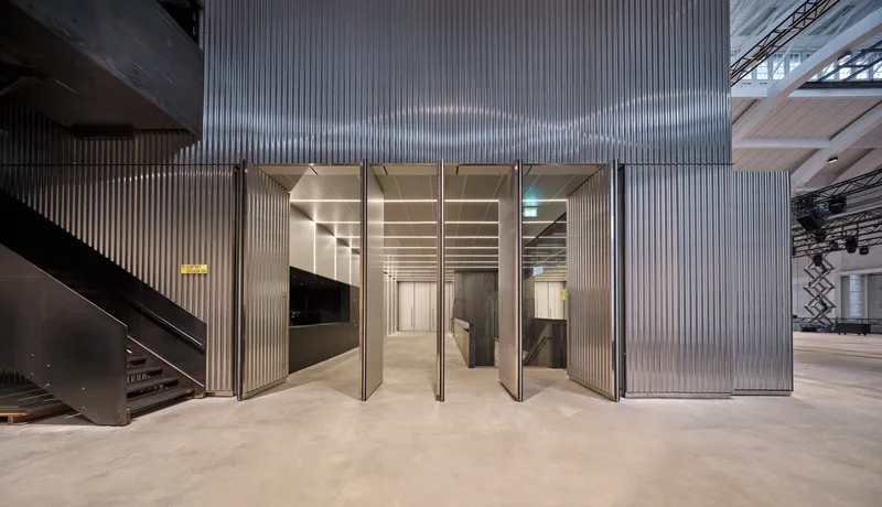Corrugated metal wall with tall folding doors opening to an interior space with polished concrete floors