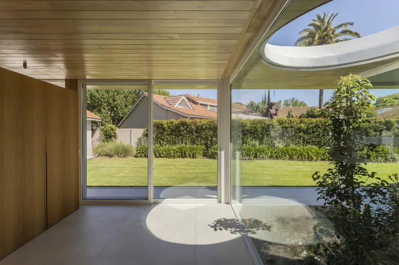 Interior view of living space with circular skylight opening and sliding doors to garden
