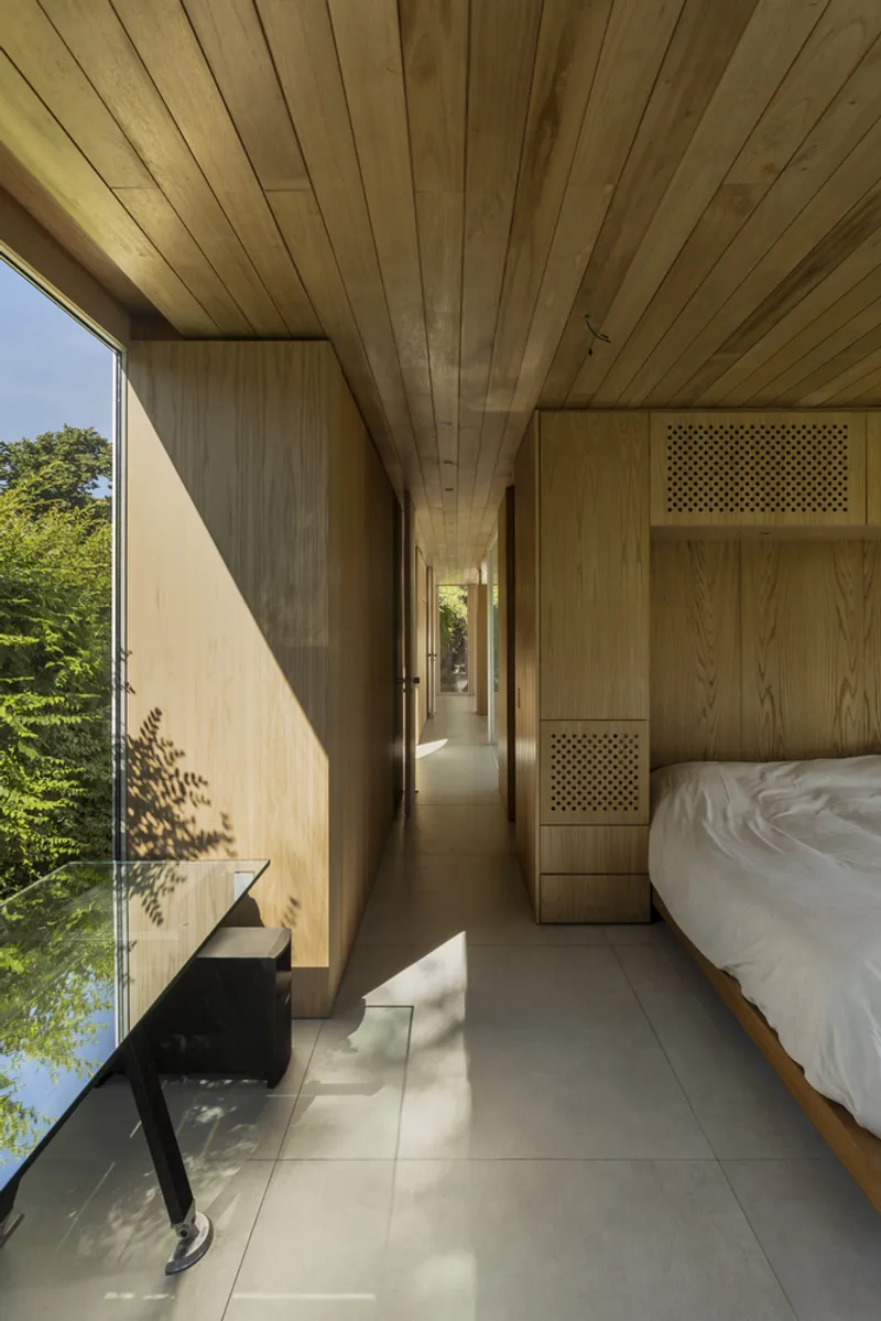 Bedroom corridor with timber-lined walls and ceiling filtering morning sunlight across the floor