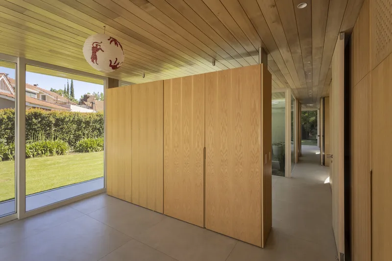 Interior corridor with oak-paneled wardrobe and slatted timber ceiling under afternoon light