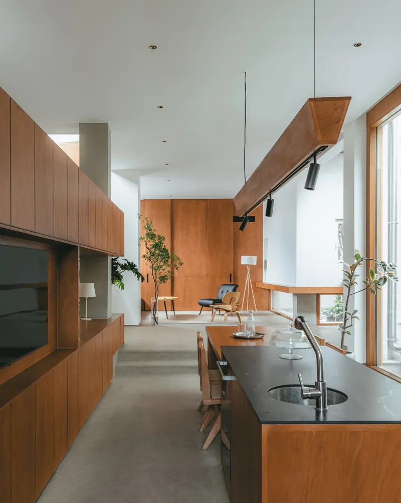 Open-plan kitchen and living space with timber cabinetry, black stone island, and polished concrete floor