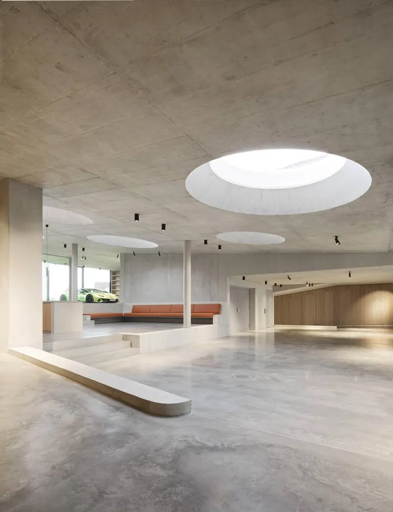 Circular skylight illuminating the interior with white columns and terrazzo flooring below concrete soffit