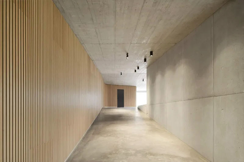 Corridor with vertical timber slat wall on one side and smooth plaster panels on the other
