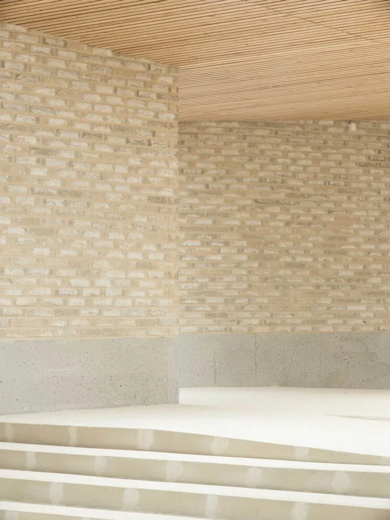 Interior corner showing pale brick walls, timber slat ceiling and terrazzo stairs descending