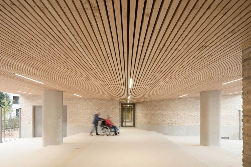 Ground floor entrance lobby with radiating timber slat ceiling and two figures moving through