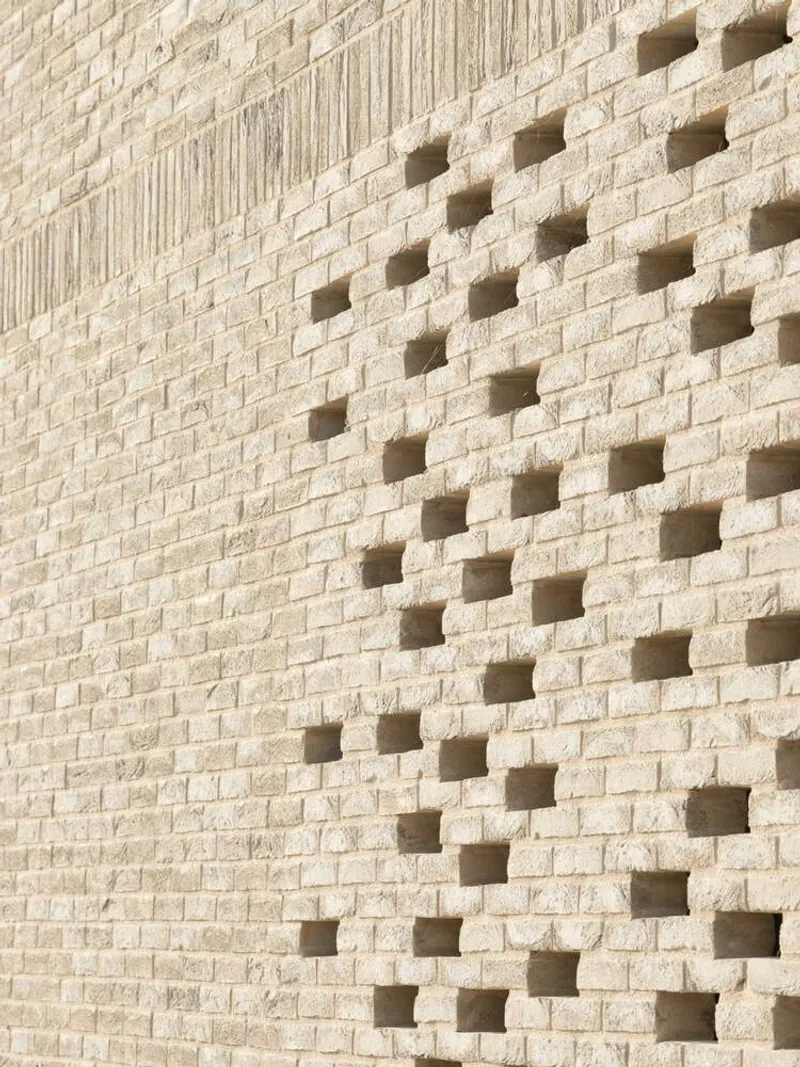 Close-up of pale brick wall with scattered square perforations casting shadows in sunlight