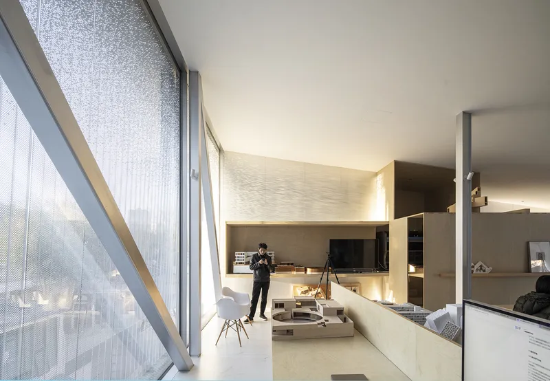Double-height living space with translucent corrugated wall and resident holding a camera