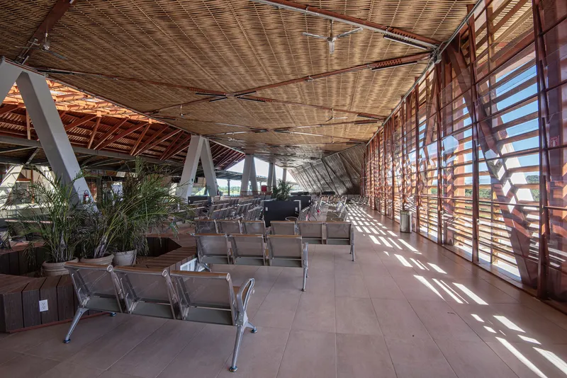 Waiting area with timber louvered facade casting sunlight across rows of seating and woven ceiling panels