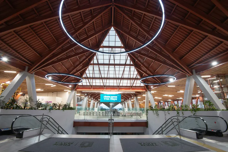 Interior concourse with pitched timber ceiling and triangular skylight framed by circular hanging light fixtures