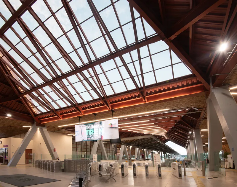 Ticket hall interior showing gridded skylight with steel structure and timber ceiling panels above access gates