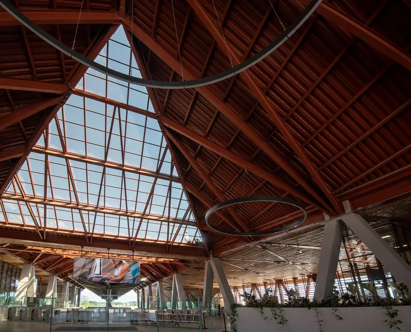 Interior view of the timber-clad ceiling with exposed diagonal trusses and triangular glazed skylight above the departure hall