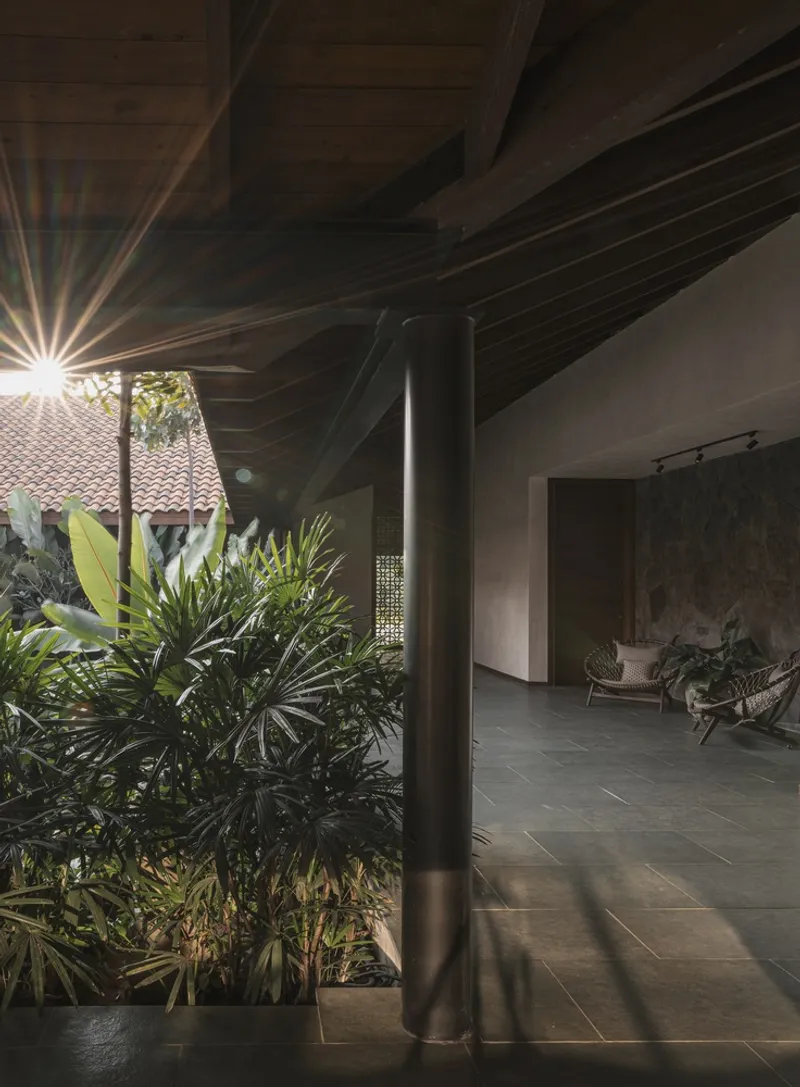 Covered walkway with steel column and timber roof beams at sunset with planted courtyard visible beyond