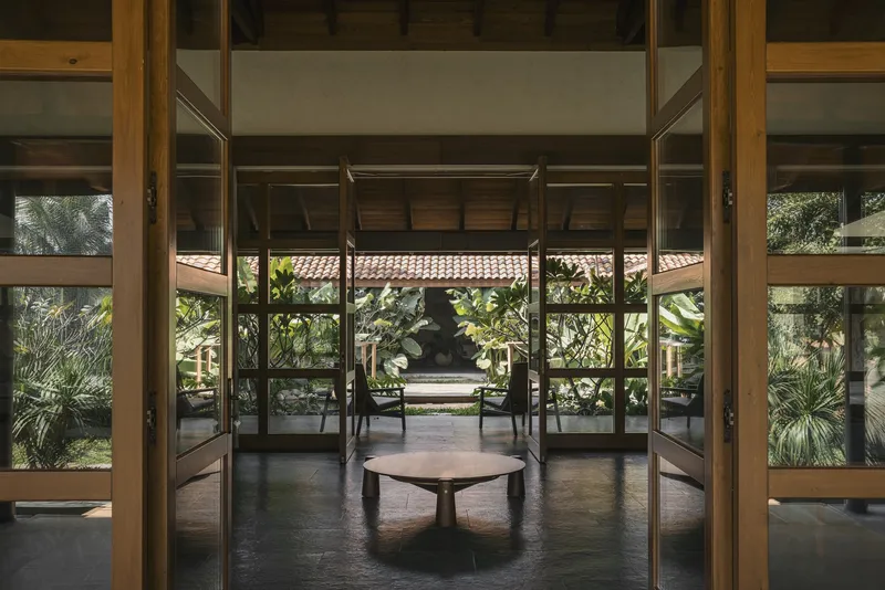 View through timber framed doors to covered corridor and courtyard garden with tile roof