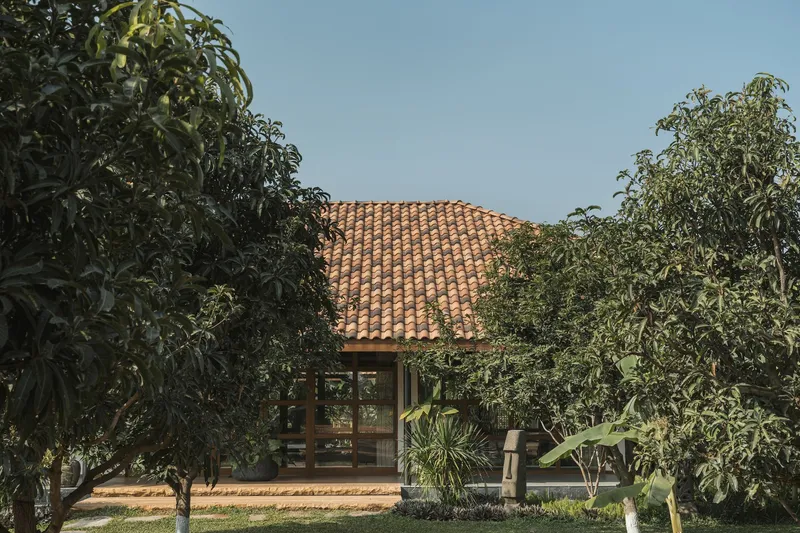 Clay tile roof pavilion nestled among dense foliage with timber deck and lawn in foreground