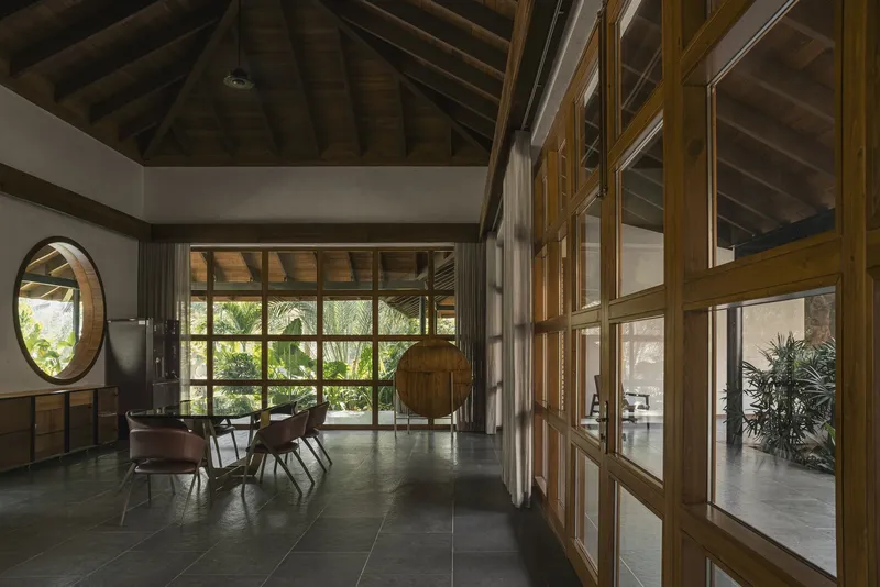 Interior hallway with circular window and timber-framed glass partitions under a vaulted wood ceiling