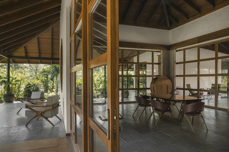 Open plan living area with timber screen partitions and covered terrace visible through gridded glazing