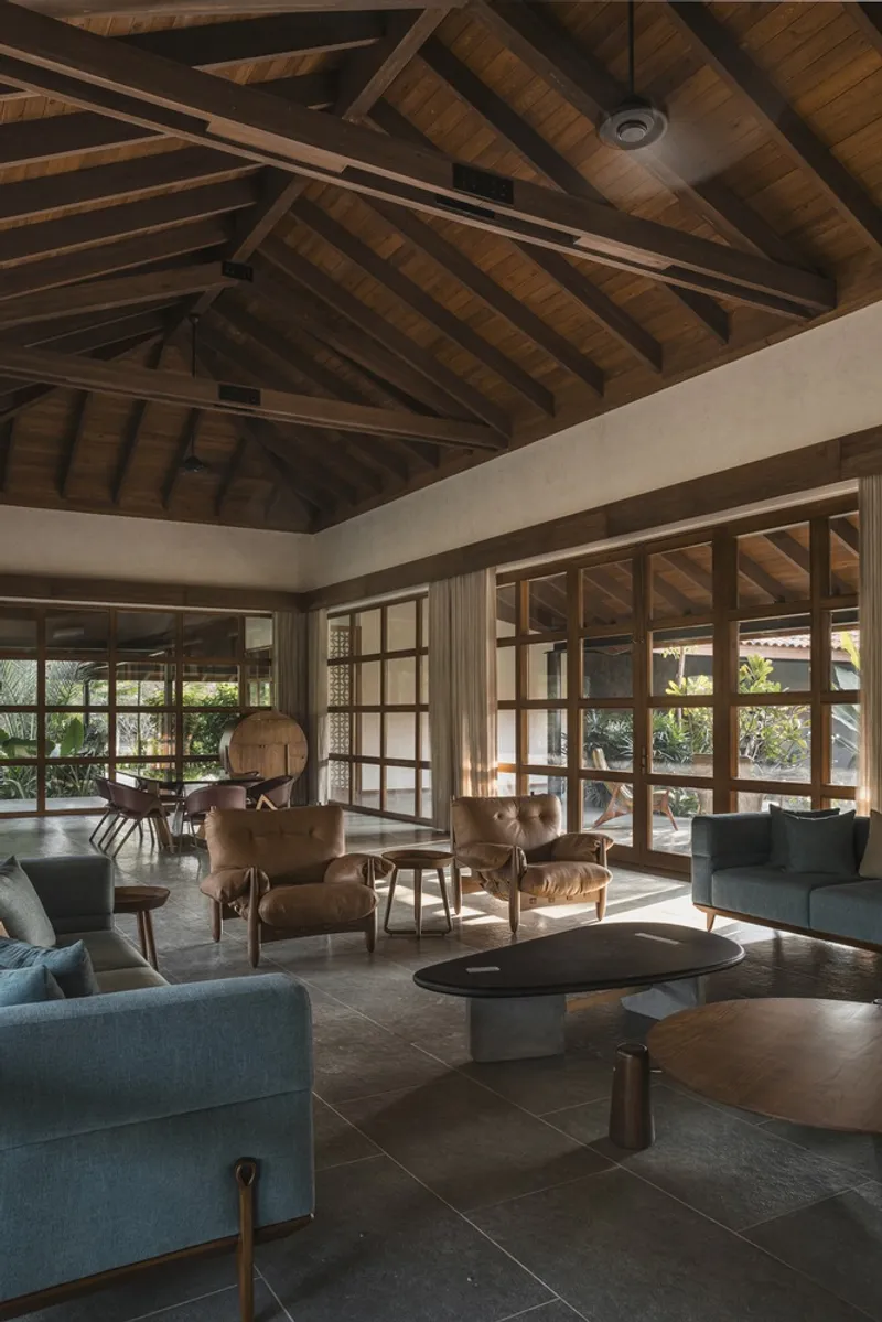 Living room with exposed timber roof trusses and gridded glass doors opening to garden views