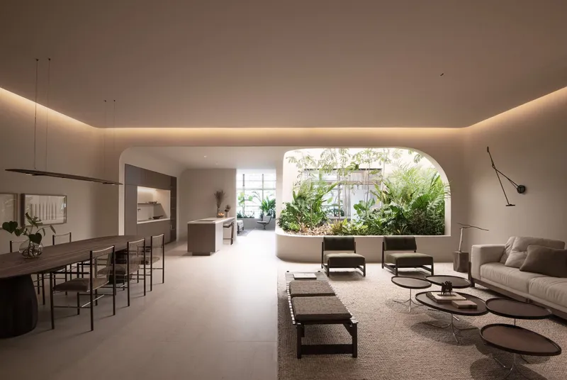 Open plan interior with dining and living areas framing an arched window to a planted courtyard