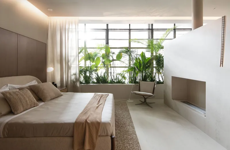 Bedroom with a planted window alcove framed by horizontal metal louvers filtering daylight