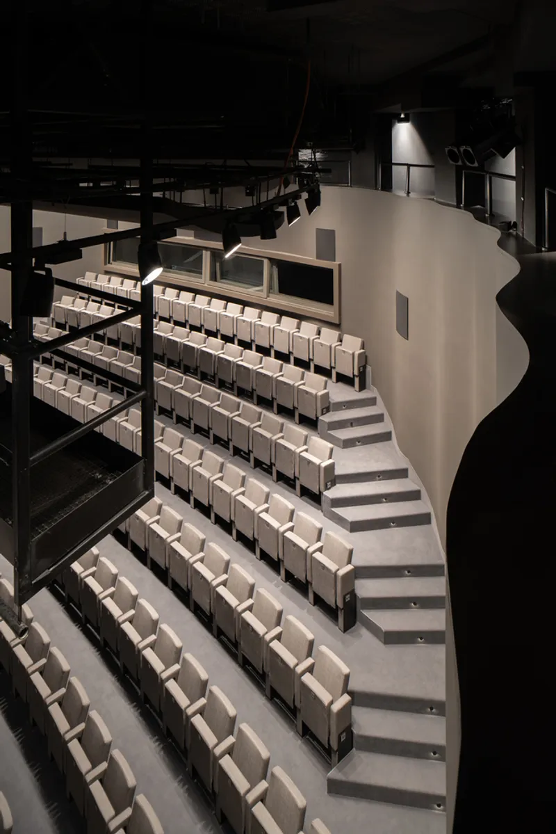 Interior view of the auditorium seating with a curved balcony edge under dramatic theatrical lighting