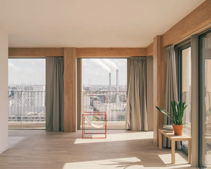 Interior living space with exposed laminated timber columns and beams framing three balcony doors