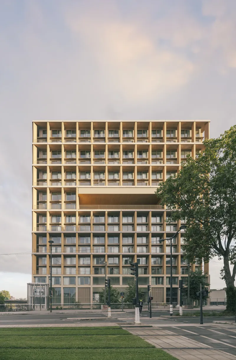 Front elevation showing the recessed mid-level floor behind the gridded timber screen at sunset