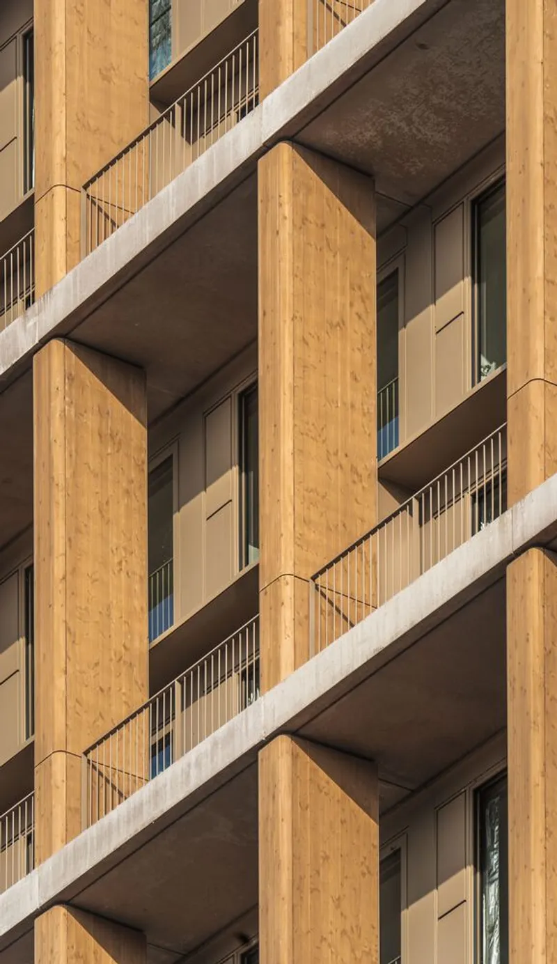 Facade detail showing staggered balconies with timber cladding and white railings in afternoon light