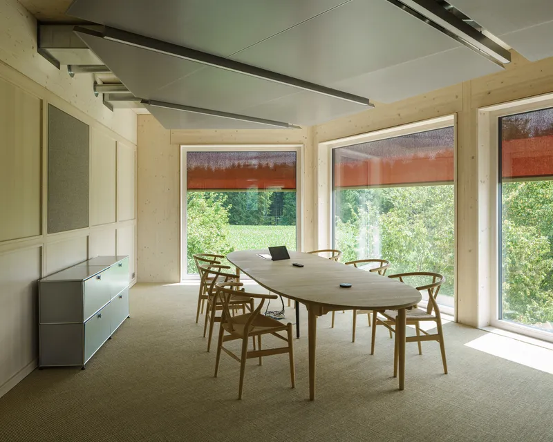 Meeting room with exposed timber ceiling and three windows overlooking greenery