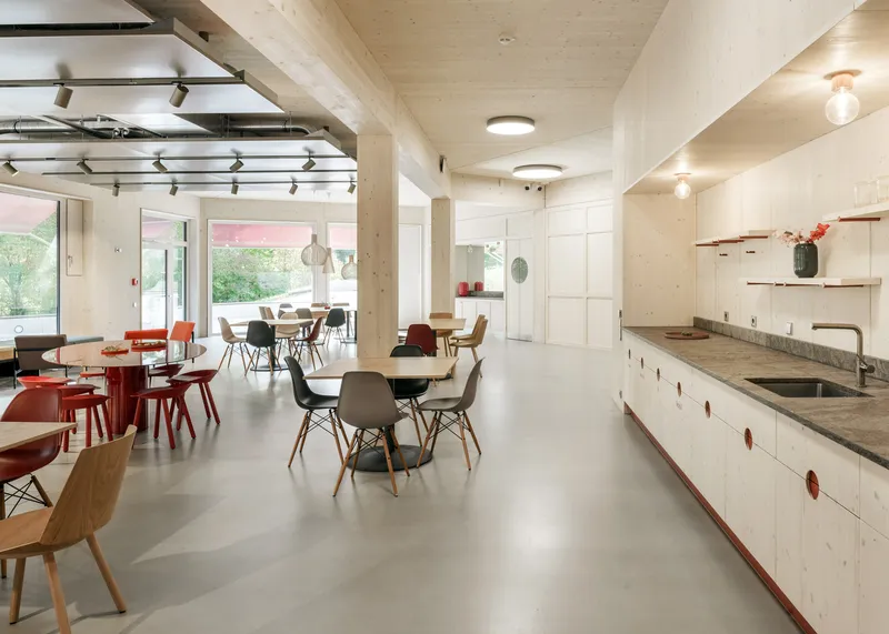 Communal kitchen and dining area with polished concrete floor and exposed timber ceiling beams