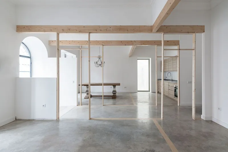 Open interior with timber frame dividing spaces and polished concrete floor extending to arched window