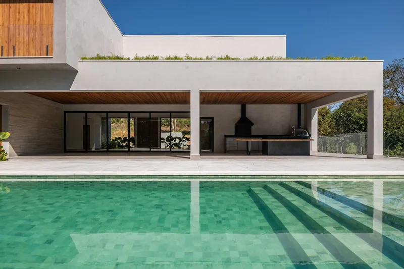 View across the swimming pool toward covered terrace with outdoor kitchen under timber soffit