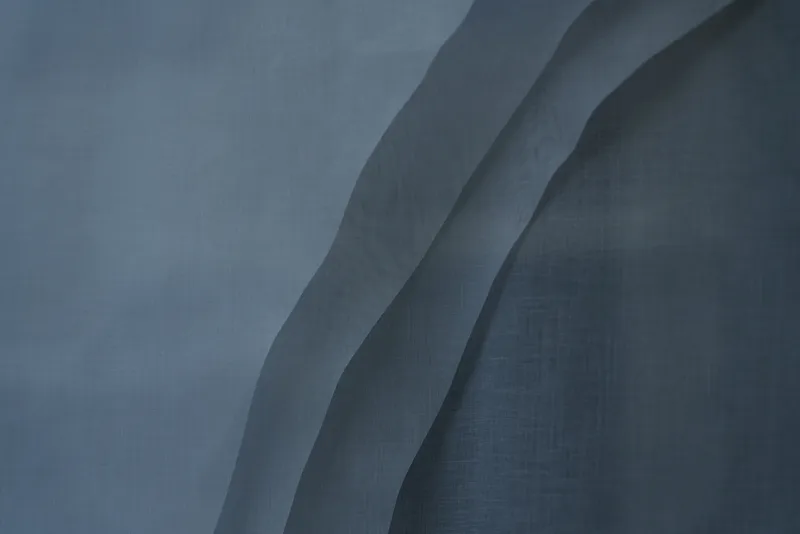 Close-up of layered grey fabric panels with diagonal folds creating subtle depth and shadow