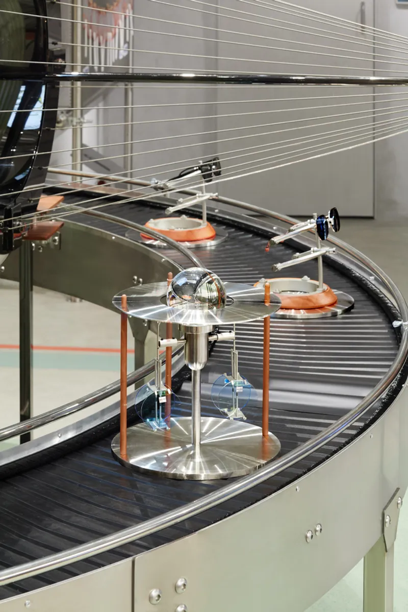 Curved conveyor belt with circular rotating platforms and suspended steel cables above