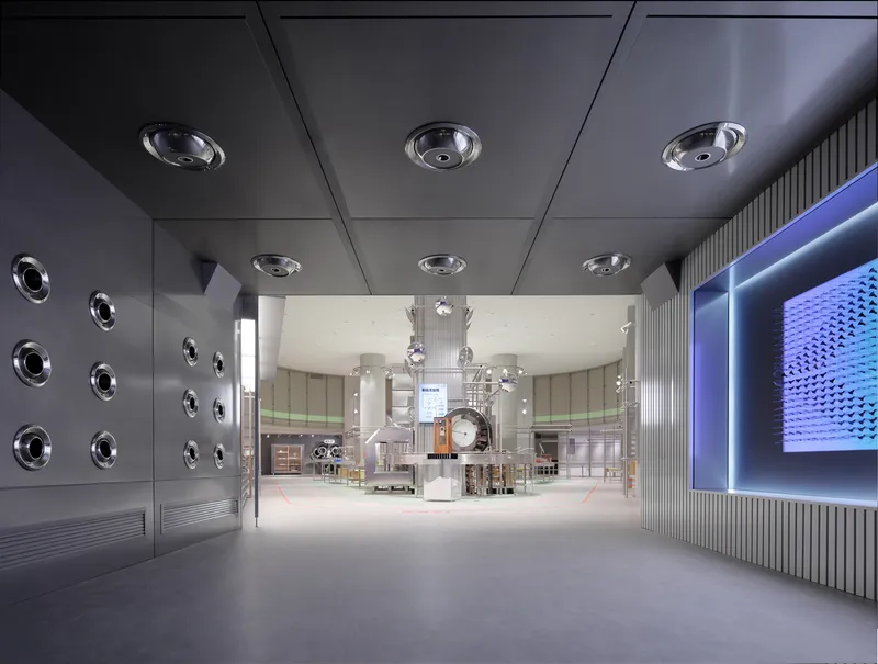 Corridor with dark ceiling featuring circular recessed fixtures leading to central lobby space
