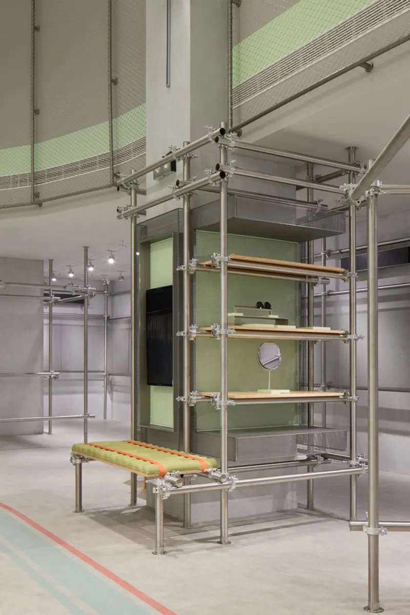 Freestanding tubular steel shelving unit with wooden shelves and a cushioned bench at the base