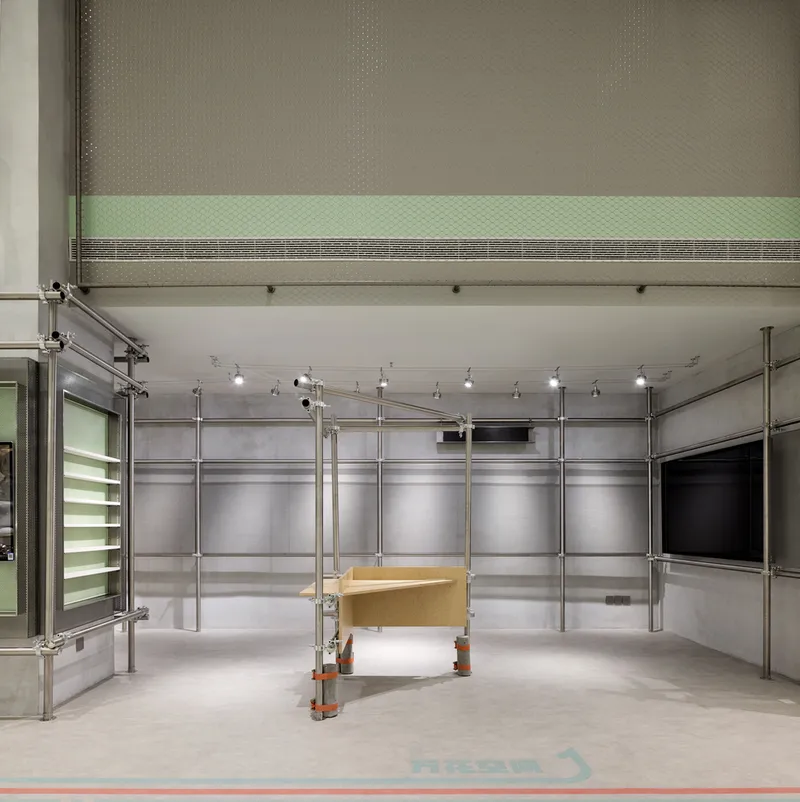 Interior retail space with modular steel scaffolding frames and translucent mesh panels under track lighting