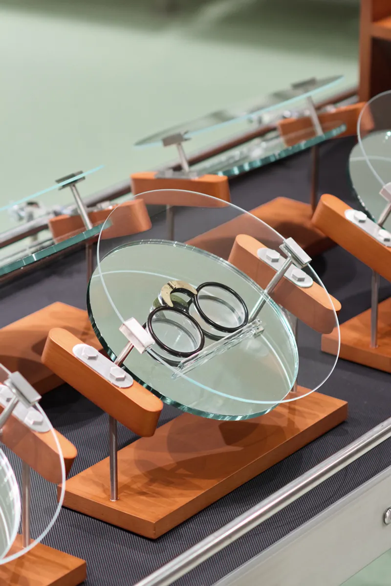 Glass display tray on wooden base holding eyewear on a motorized conveyor belt