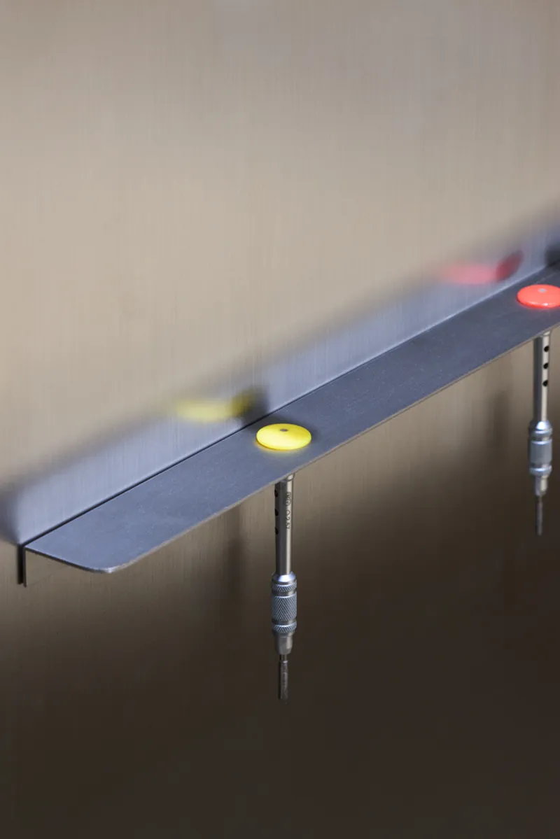 Close-up of adjustable leveling feet with colored plastic caps on a metal frame edge