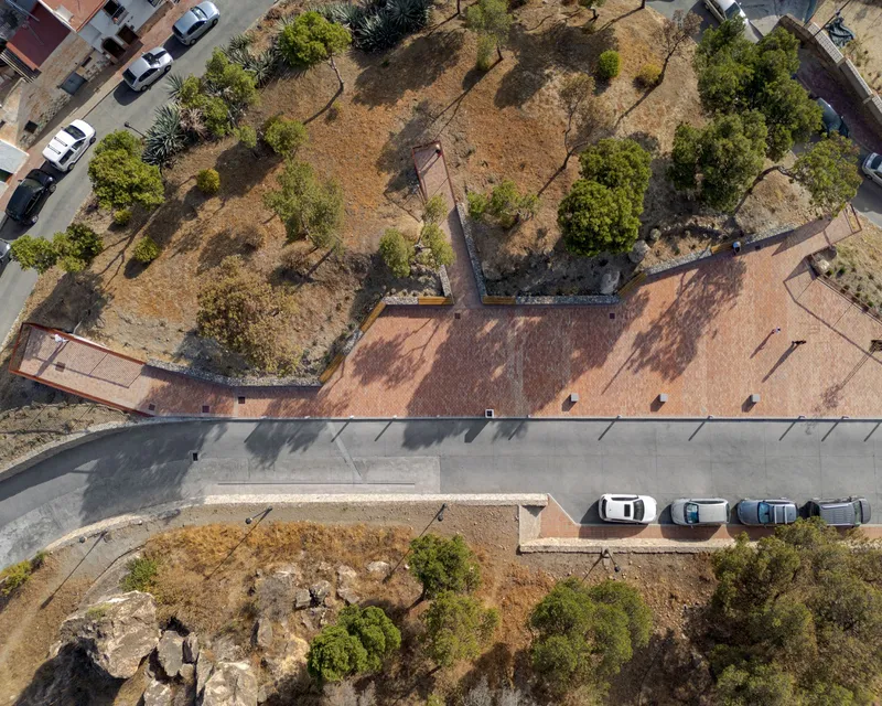 Drone view of the terraced hillside plaza connecting the parking area to the planted slopes and pathways