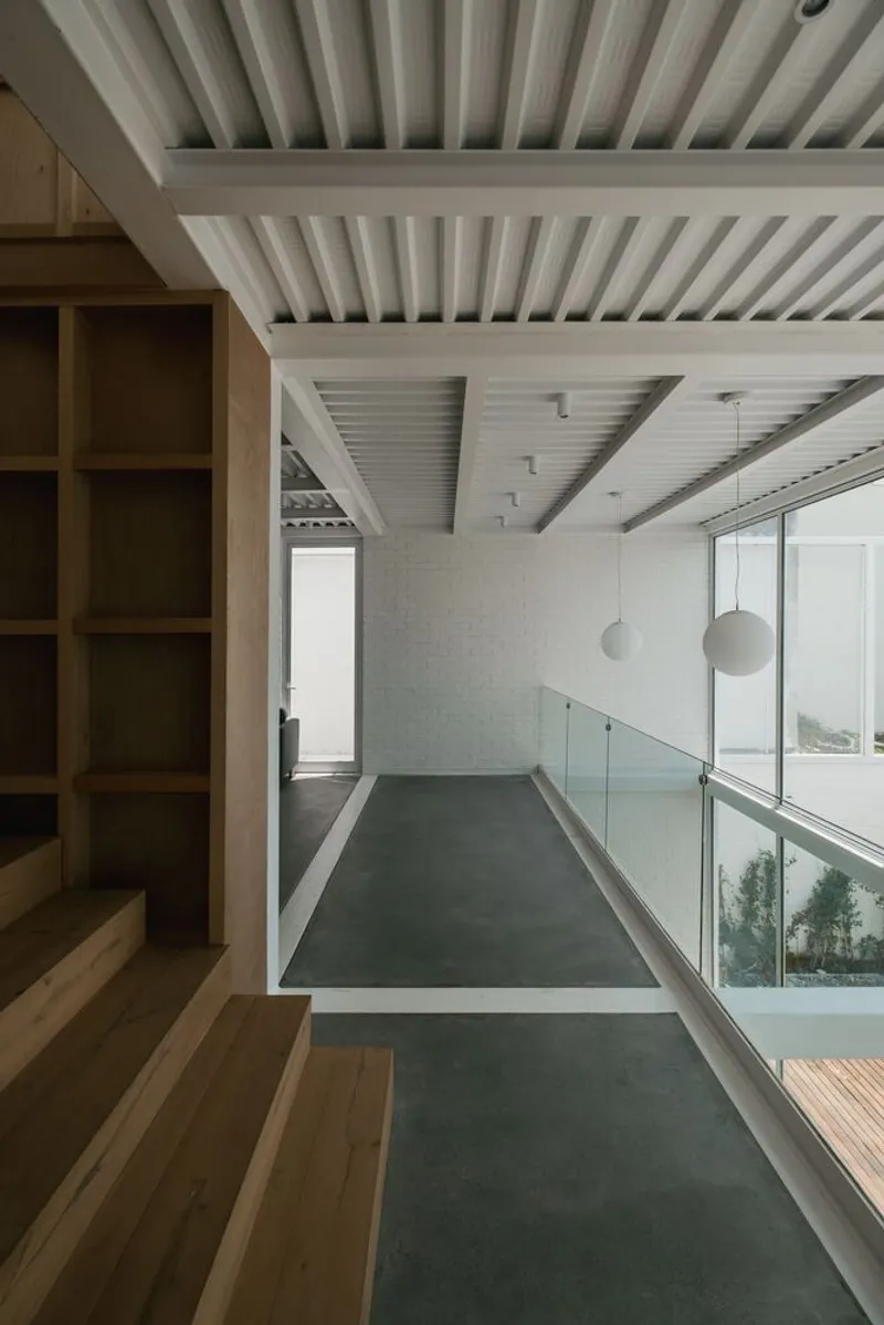 Interior hallway with exposed timber beam ceiling and glass railing overlooking the courtyard below