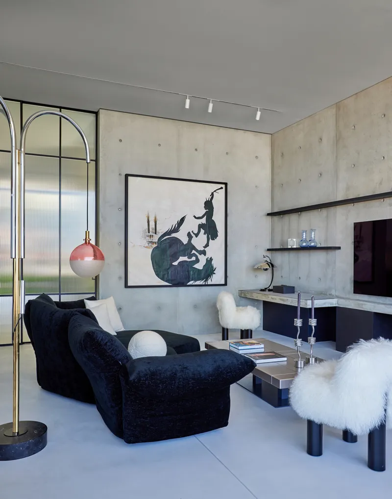 Sitting room with concrete walls, floating shelves, and arched glass partition reflecting in the background