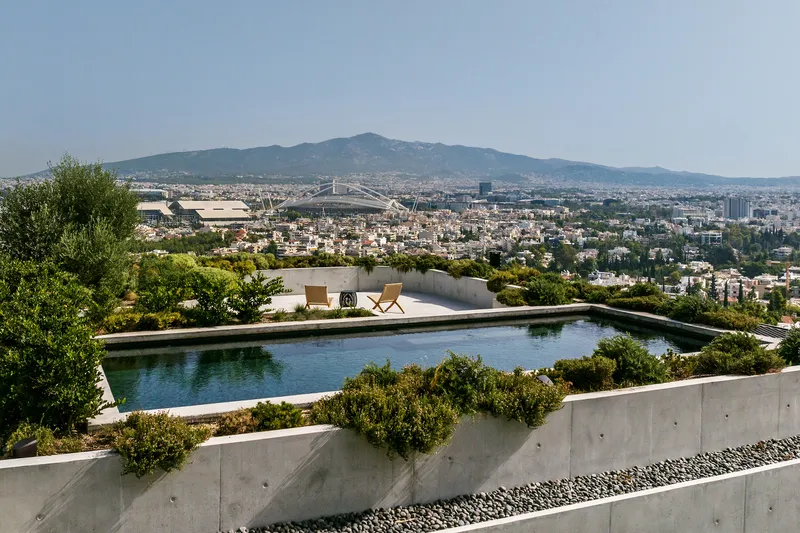 Rooftop pool with folding chairs on deck and concrete retaining walls among planted vegetation