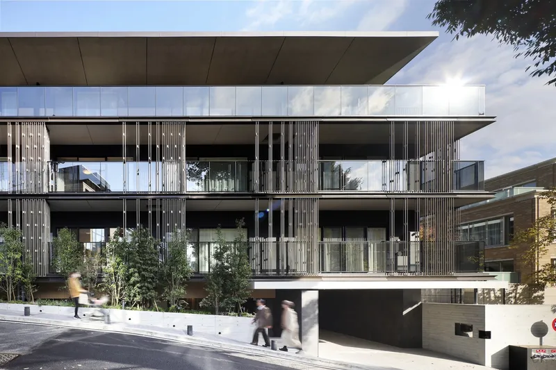 Street view of the layered facade with vertical timber screening and planted terraces with pedestrians passing