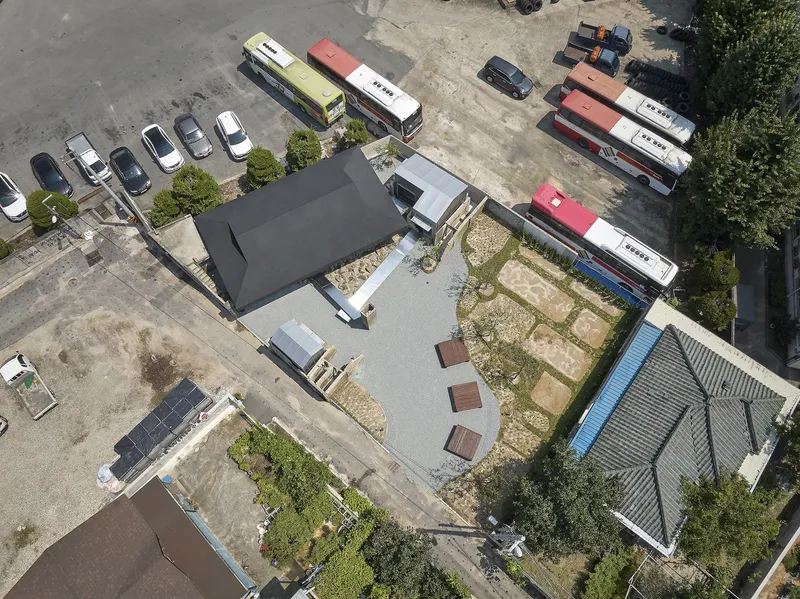 Aerial view of the pavilion complex with gravel courtyards surrounded by parked buses and trees