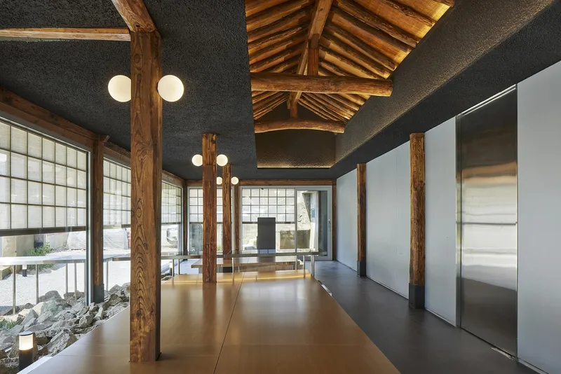 Interior space with reclaimed timber columns, exposed roof structure, and polished resin floor